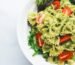 Pesto pasta with sliced tomatoes served on white ceramic plate